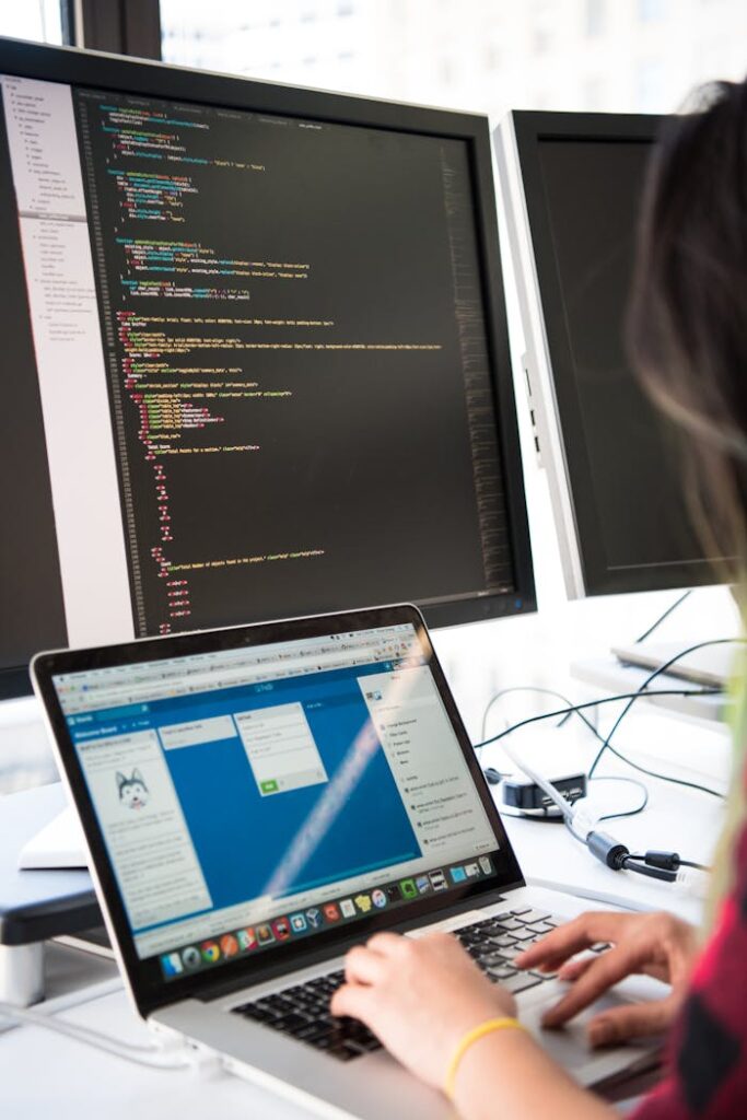 pexels-photo-1181673 Programmer working on code across multiple screens in a modern office setting.